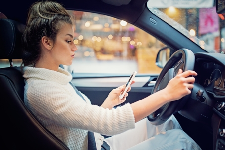 Woman texting/looking at her phone while behind the wheel