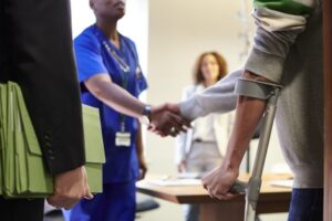 Man on crutches shaking hand of doctor